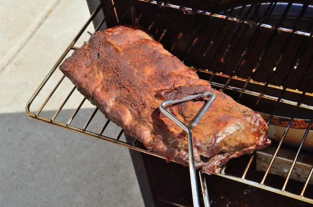Removing baby back ribs from an electric barbecue smoker