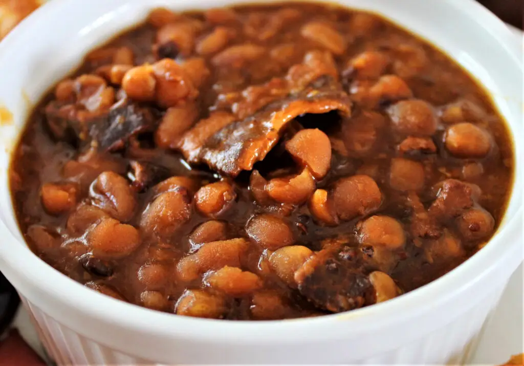 Homemade baked beans with bacon in a white serving bowl
