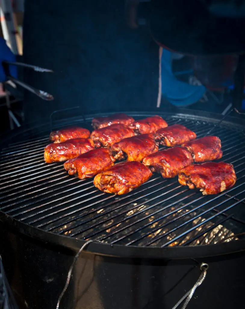 BBQ chicken thighs glazed with barbecue sauce on a smoker