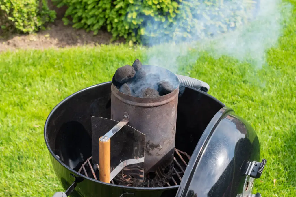 Smoking charcoal chimney starter on a kettle grill