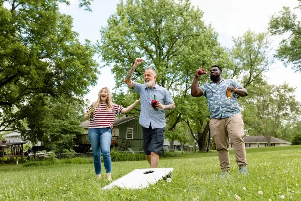 Friends playing cornhole at a backyard barbecue