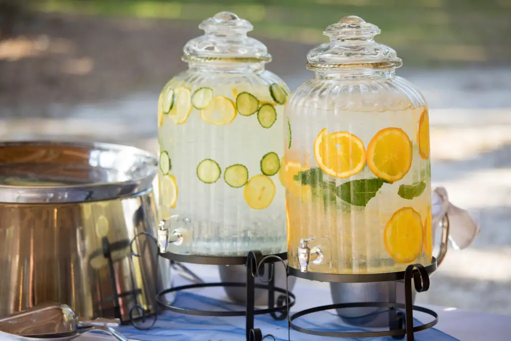Fruit-infused ice water in dispensers on a table in a backyard