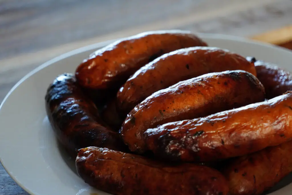 Grilled barbecue sausages resting on a white serving plate