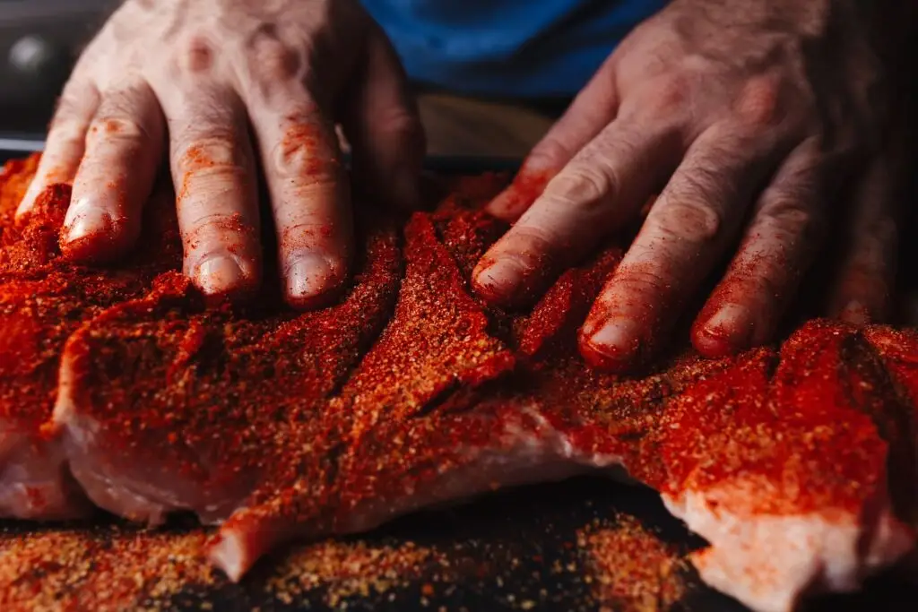 Man applying barbecue rub to meat