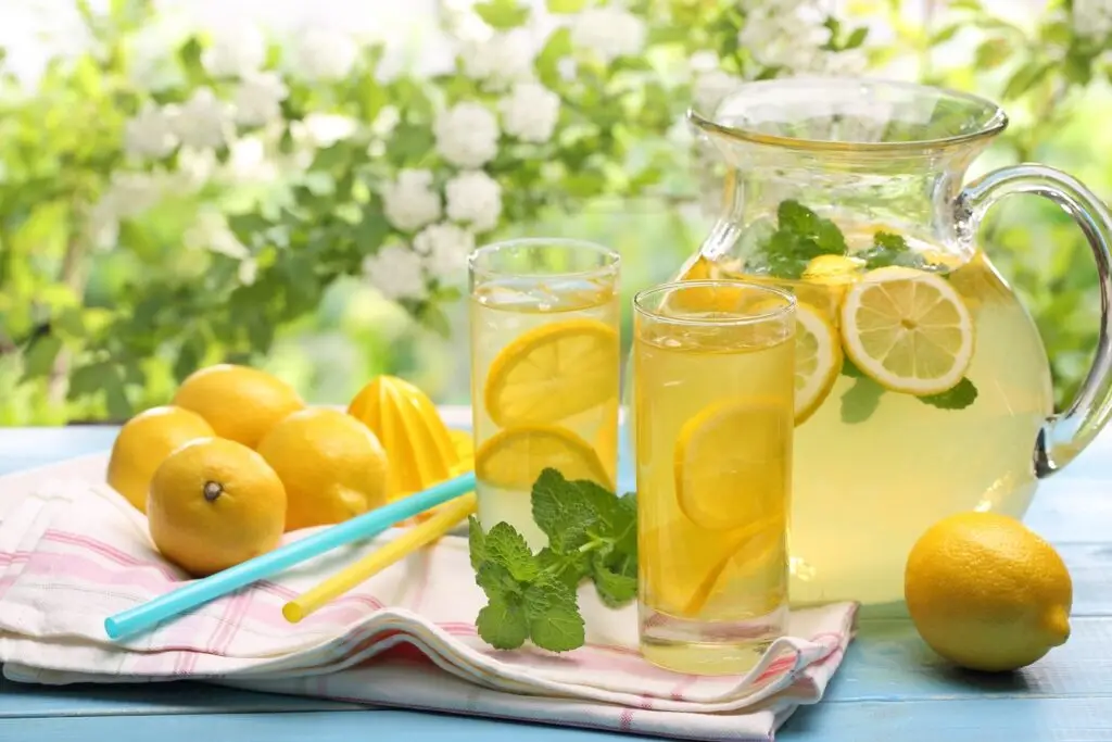 Pitcher and glasses of lemonade on a picnic table in a garden