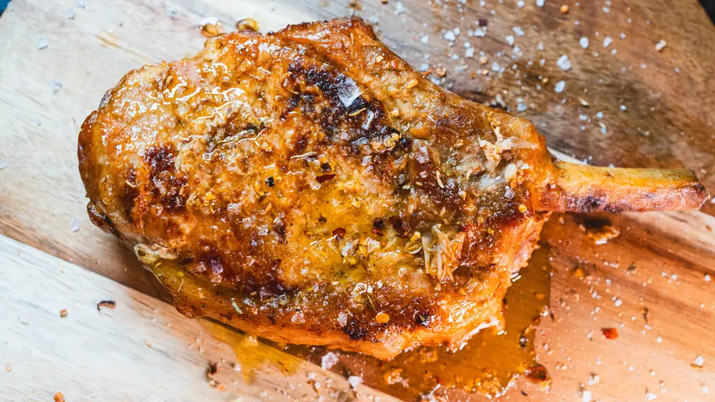Juicy grilled pork chop resting on a wooden cutting board