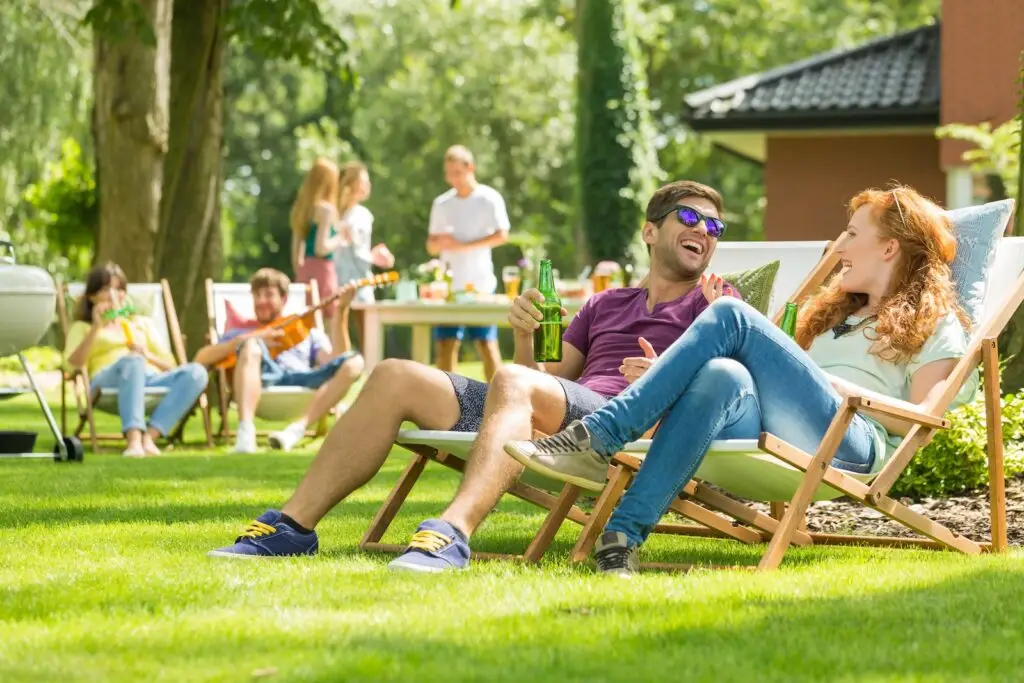 People at a barbecue sitting in lawn chairs having a conversation